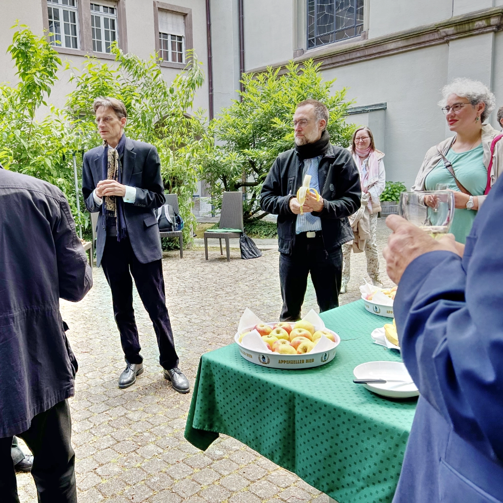Sänger und Sängerinnen der Kantorei der Chorakademie Freiburg stehen vor der Kirche St. Marien in Basel und Herr Prof. Böhmann hält eine Rede.