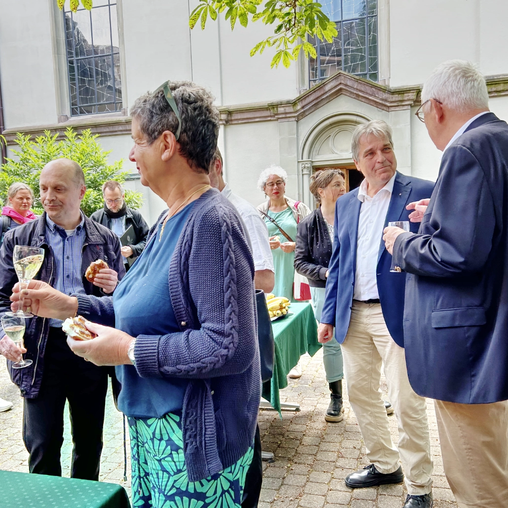 Sängerinnen und Sänger der Chorakademie Freiburg stehen zusammen und trinken einen Sekt