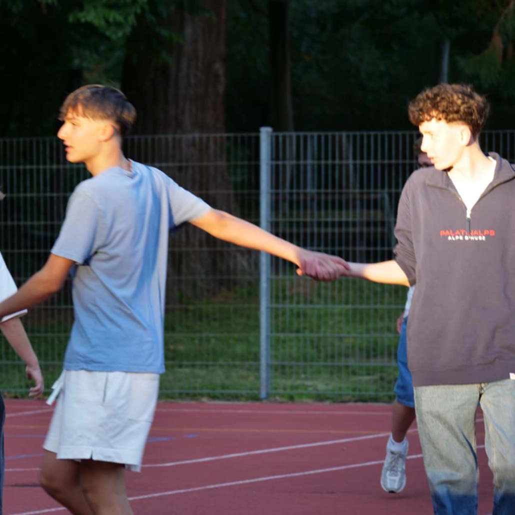 Zwei Jungen im Teenageralter klatschen sich High Five. Sie stehen auf einem Fussballplatz