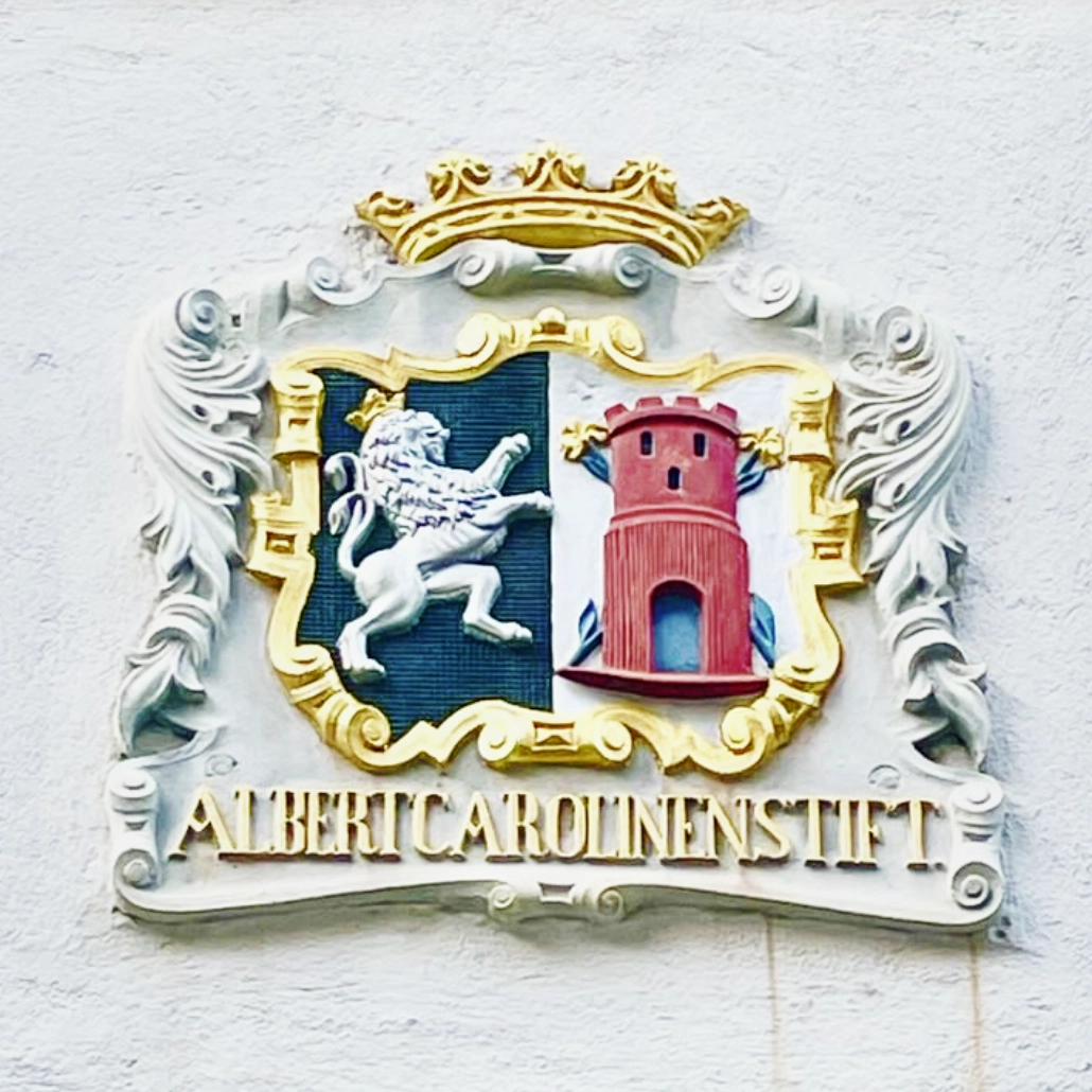 Wappen Pilgerstab 1030 x 1030 Auf dem Logo des Haus zum Pilgerstab sieht man ein Wappen. Darin ein Löwe mit einer Krone und eine rote Burg. Darunter steht der Text Albert Carolinenstift